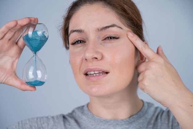 Retrato de una mujer sosteniendo una bombilla contra un fondo azul