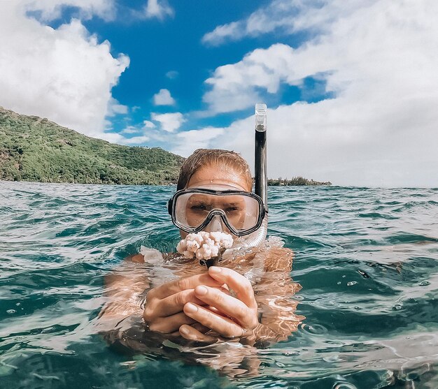 Retrato de una mujer sosteniendo un coral en el mar