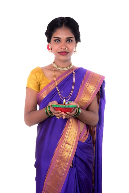 Retrato de una mujer sosteniendo diya, Diwali o deepavali foto con manos femeninas sosteniendo la lámpara de aceite durante el festival de la luz en la pared blanca