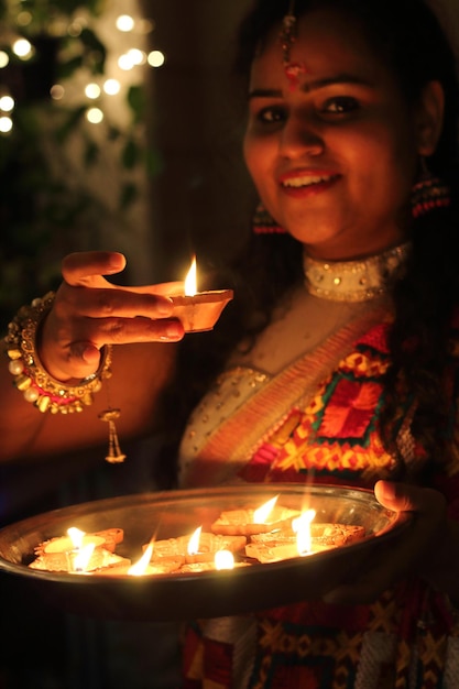 Retrato de una mujer sosteniendo una diya iluminada por la noche