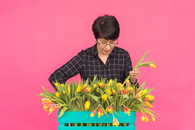 Foto retrato de una mujer sosteniendo una flor rosa contra un fondo rojo