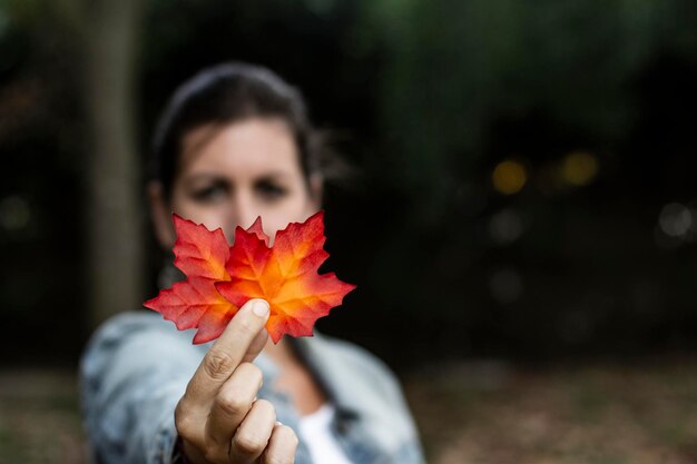 Foto retrato de una mujer sosteniendo una hoja durante el otoño