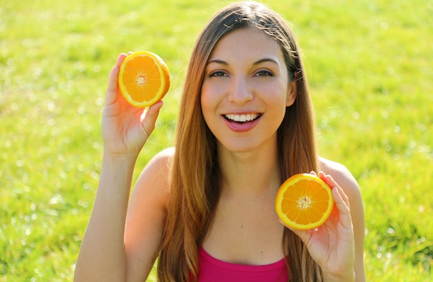 Foto retrato de una mujer sosteniendo mitades de naranja