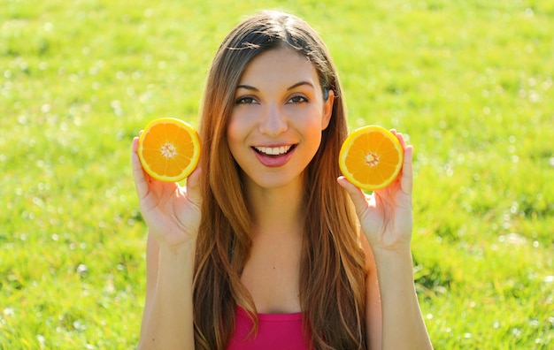 Foto retrato de una mujer sosteniendo mitades de naranja