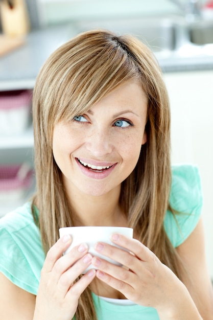 Retrato de una mujer sosteniendo una taza de té en la cocina