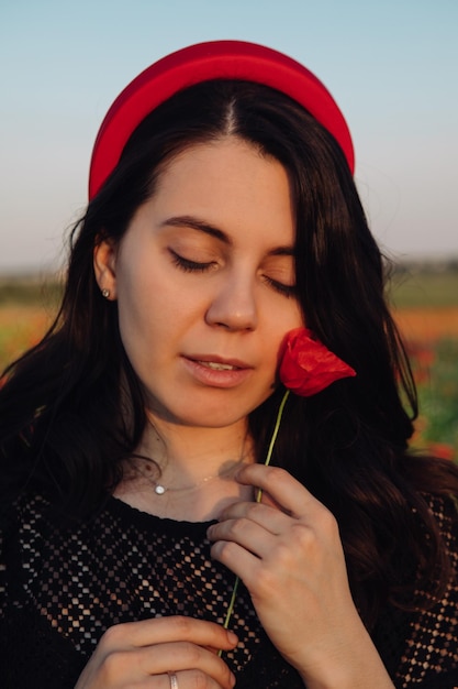 Retrato de mujer suave con flores de amapola al atardecer de cerca