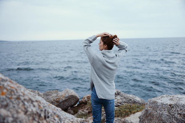 Retrato de una mujer suéteres mar nublado admirando la naturaleza vista posterior inalterada