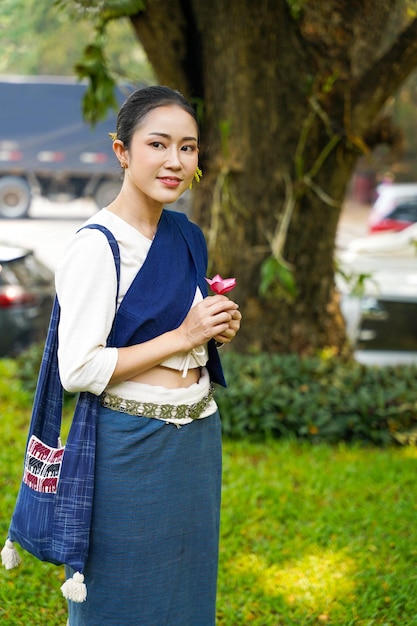 Foto retrato de una mujer tailandesa vestida con un vestido tradicional del norte de tailandia actuando para una sesión de fotos en un parque público