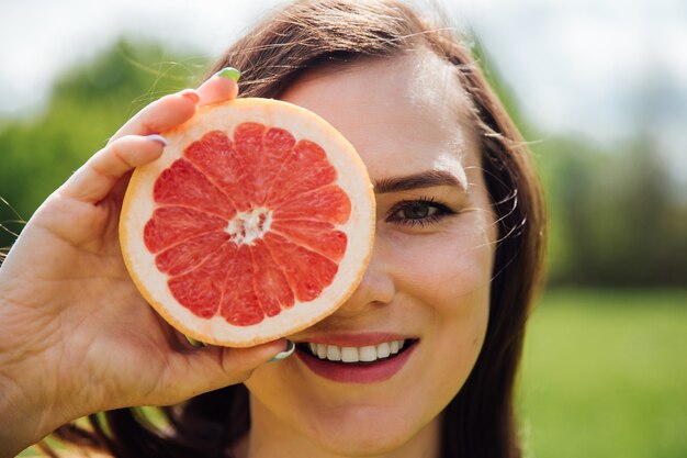 Retrato de mujer tapándose los ojos con pomelo