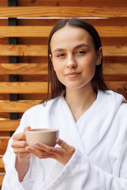 Retrato de una mujer con una taza de té en la terraza después de los tratamientos de spa