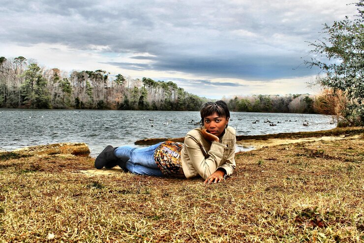 Foto retrato de una mujer tendida en la orilla del lago contra un cielo nublado