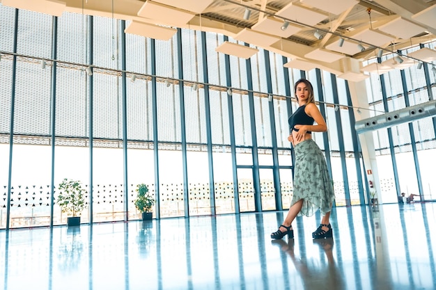 Retrato de una mujer en la terraza de un mirador de la ciudad en un edificio de cristal con falda verde