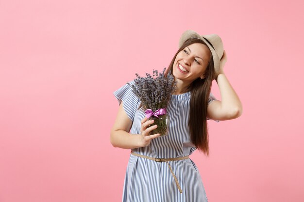 Retrato de una mujer tierna joven feliz en vestido azul, sombrero con ramo de hermosas flores de lavanda púrpura aisladas sobre fondo rosa de tendencia brillante. Concepto de vacaciones del día internacional de la mujer.