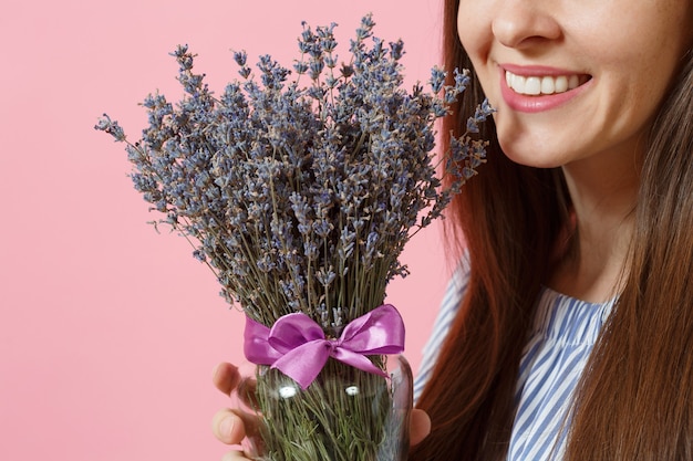 Retrato de una mujer tierna joven feliz en vestido azul, sombrero con ramo de hermosas flores de lavanda púrpura aisladas sobre fondo rosa de tendencia brillante. Concepto de vacaciones del día internacional de la mujer.