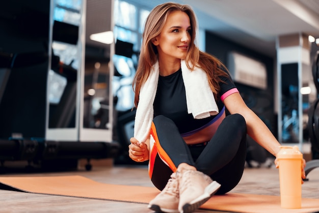 Retrato de una mujer con una toalla trabajando en un gimnasio