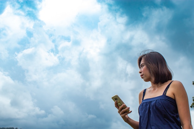 Retrato de una mujer tocando el teléfono y el cielo.