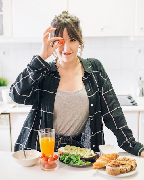 Foto retrato de una mujer con tomate cherry frente a su ojo