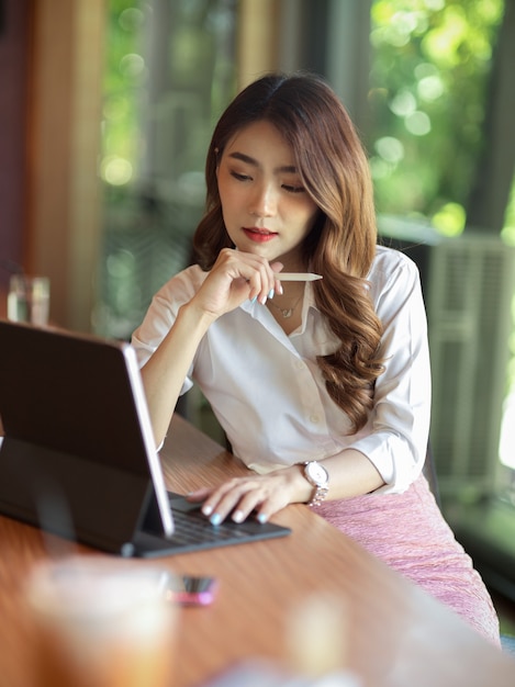 Retrato de mujer trabajadora exitosa pensando en su trabajo con tableta digital con lápiz óptico