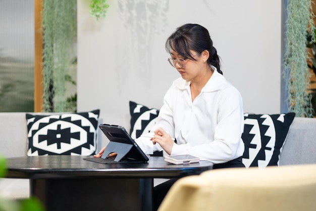 Retrato de mujer trabajadora mujer de negocios ocupada trabajando en una tableta digital en un espacio de trabajo de oficina moderada atractiva hermosa mujer de negocios asiática trabajando en la oficina en casa