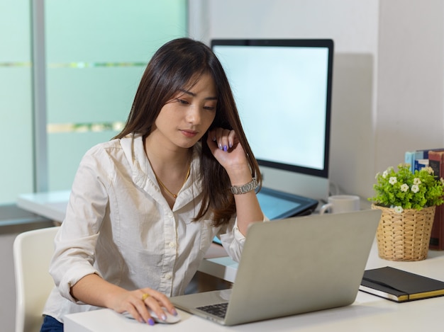 Retrato de mujer trabajadora de oficina trabajando con un portátil en la sala de oficina moderna