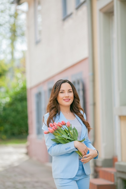 Retrato de una mujer con un traje azul con un ramo de tulipanes