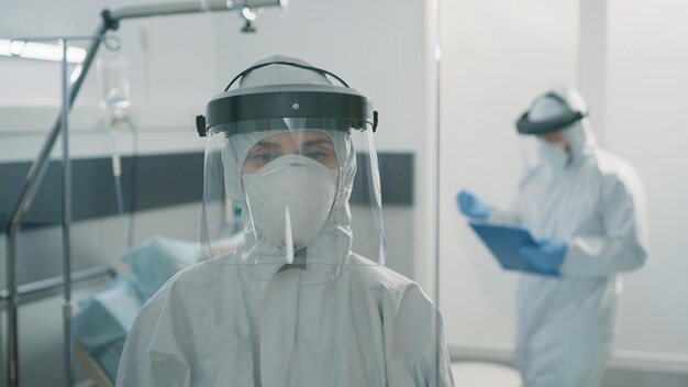 Retrato de mujer con traje protector contra el brote de coronavirus en la zona de bloqueo. Primer plano de paramédico con uniforme de materiales peligrosos en el área infectada por virus con infección contagiosa.