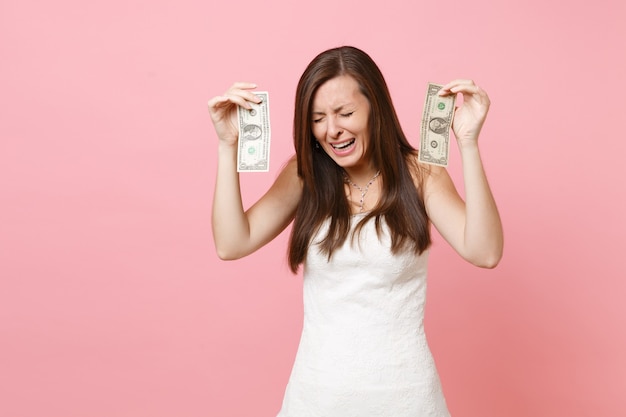 Retrato de mujer triste molesta en vestido blanco llorando y sosteniendo billetes de un dólar