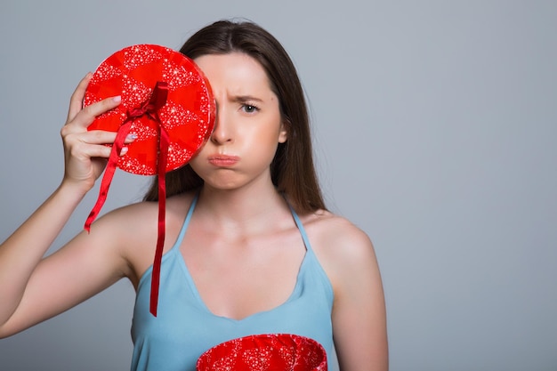 Retrato de una mujer triste de pie con una caja de regalo abierta aislada en un blanco