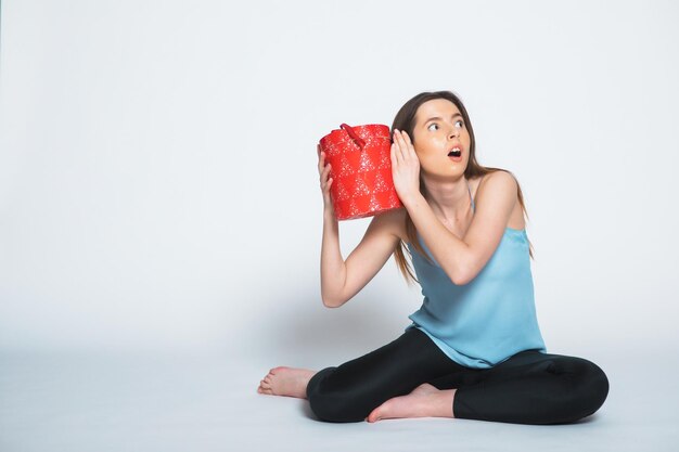 Retrato de una mujer triste de pie con una caja de regalo abierta aislada en un blanco