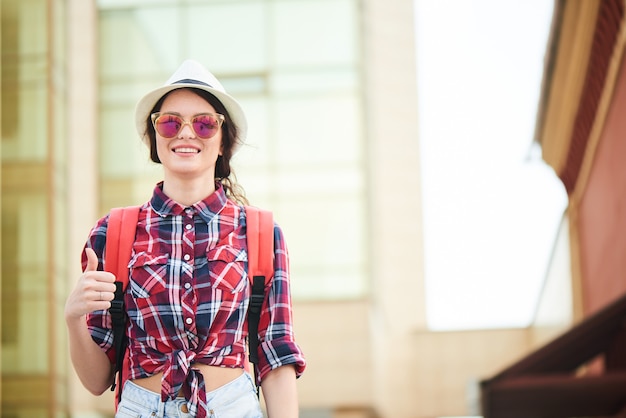 Foto retrato de una mujer turista mostrando los pulgares para arriba en la ciudad