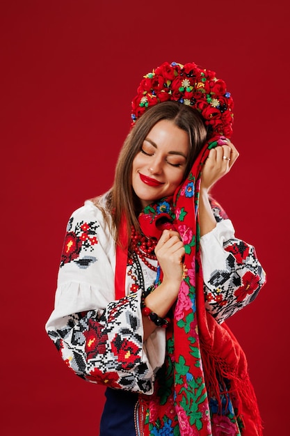 Retrato de mujer ucraniana en ropa étnica tradicional y corona floral roja con pañuelo sobre fondo de estudio viva magenta Vestido bordado nacional ucraniano llamada vyshyvanka