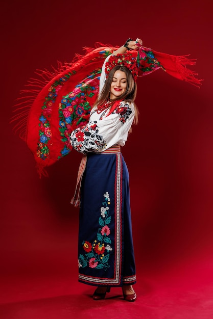 Retrato de mujer ucraniana en ropa étnica tradicional y corona floral roja sobre fondo de estudio viva magenta gira un pañuelo vestido bordado nacional ucraniano llamada vyshyvanka