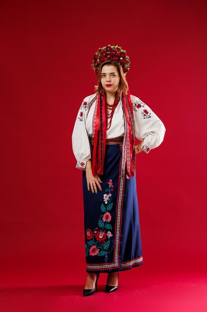 Retrato de mujer ucraniana en ropa étnica tradicional y corona floral roja sobre fondo de estudio viva magenta Vestido bordado nacional ucraniano llamada vyshyvanka Ore por Ucrania