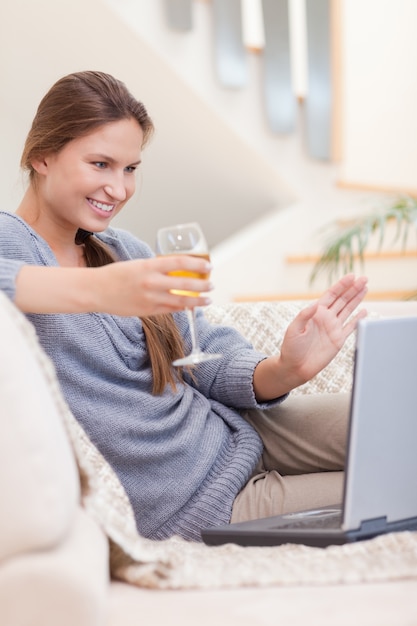 Retrato de una mujer con un vaso de vino blanco durante una videoconferencia