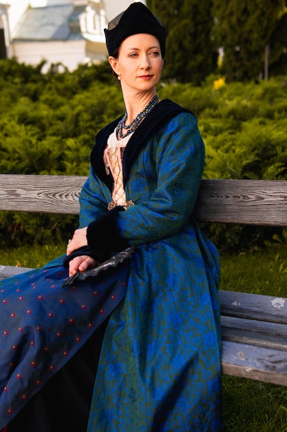Foto retrato de mujer vestida con ropa barroca histórica azul con peinado de moda antigua al aire libre