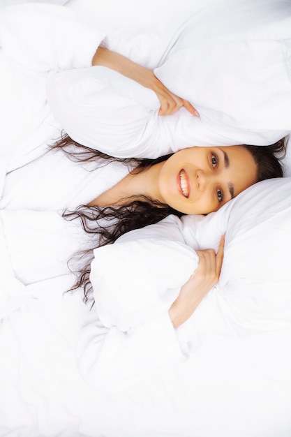 Retrato de mujer en la vista superior de almohadas. La niña se esconde en las almohadas.