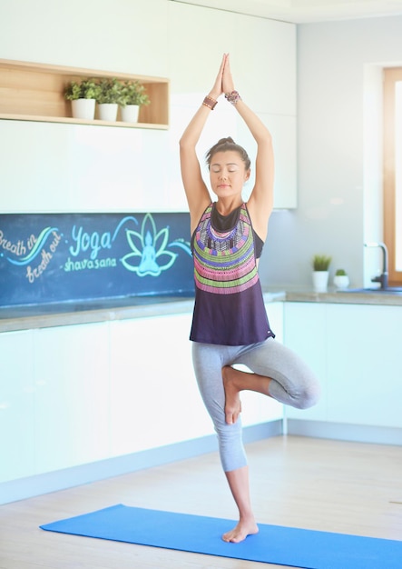 Retrato de una mujer de yoga sonriente sentada en una colchoneta de yoga después de hacer ejercicio en el estudio de yoga