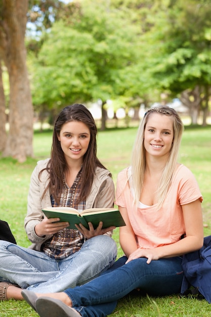 Retrato de mujeres adolescentes sentados con un libro de texto