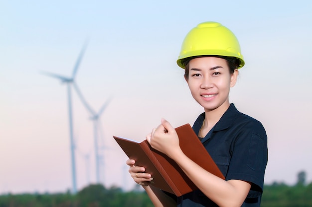 Retrato mujeres asia ingeniero trabajando y sosteniendo planos en la granja de la turbina de viento