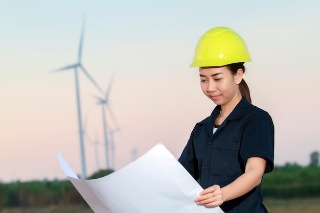 Retrato mujeres asia ingeniero trabajando y sosteniendo planos en la granja de la turbina de viento