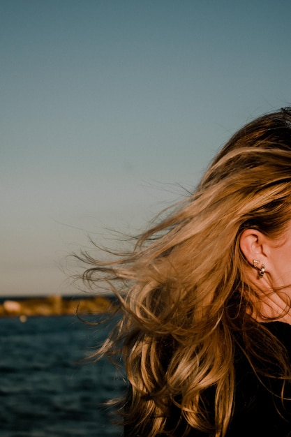Retrato de mujeres con el cabello rubio ondeando en el viento contra el cielo