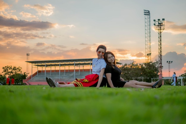 Retrato de mujeres jóvenes sonrientes sentadas en la hierba durante la puesta de sol