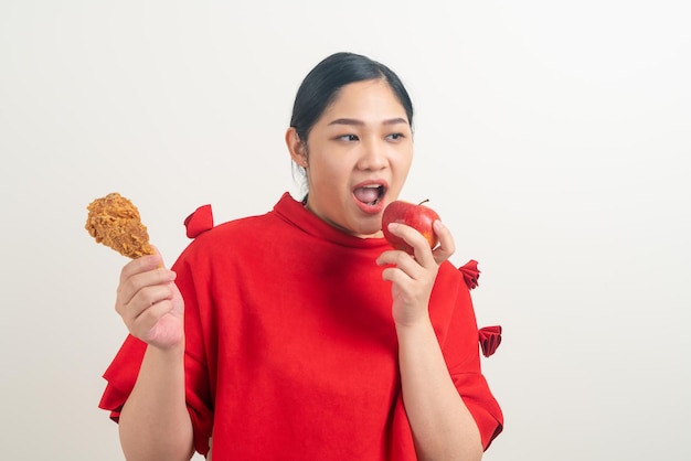 retrato mulher asiática com frango frito e maçã na mão para escolha