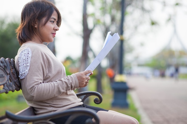 Retrato mulher asiática sentada lendo um documento.