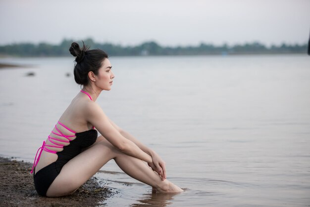 Retrato Mulher bonita em trajes de banho com um maiô de uma peça lindo corpo esportivo caminhando e posando em uma praia