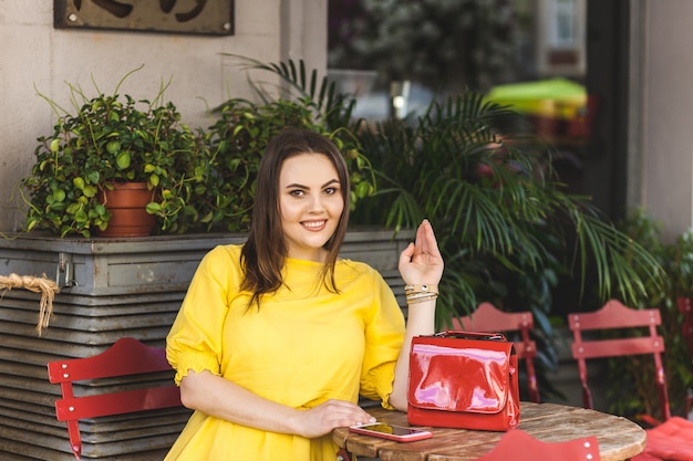 Retrato mulher bonita no vestido de verão, sentado nas mesas de um café de rua