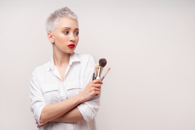 Retrato mulher com cabelo curto com pincel de maquiagem na mão