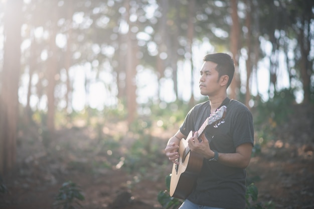 Retrato músico hombre con guitarra en el bosque