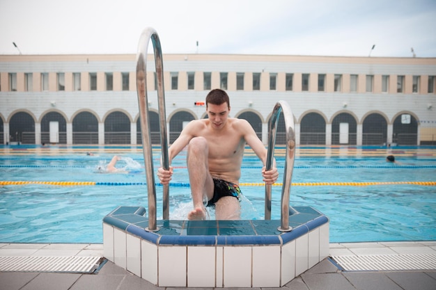 Retrato de un nadador en forma en la piscina mirando a la cámara Retrato de un nadador masculino competitivo cerca de la piscina