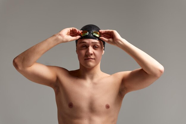 Retrato de un nadador con una gorra y una máscara Retrato a mitad de longitud de un joven nadador atleta con un gorro y una gorra